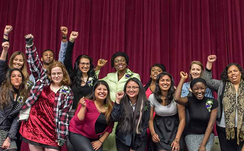 MC students and faculty posing on stage with fists in air